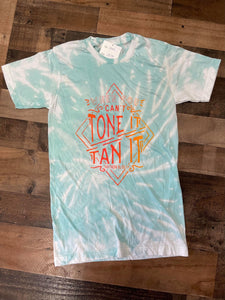 Our Tan it Tone it Tee is a soft to the touch aqua bleach dyed tee. She features a printed design that reads, “If you Can't Tone it Tan it.”   These shirts are hand dyed. Color, bleach, and dye pattern will vary on each shirt.