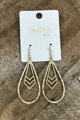 Our Maci Earrings are a matte gold hammered metal teardrop shaped earring with a chevron dangle. They drop 2.5 inches. She is perfect to add a little flare to any outfit!